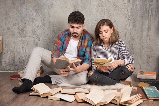 bella coppia leggendo libri seduti sul pavimento