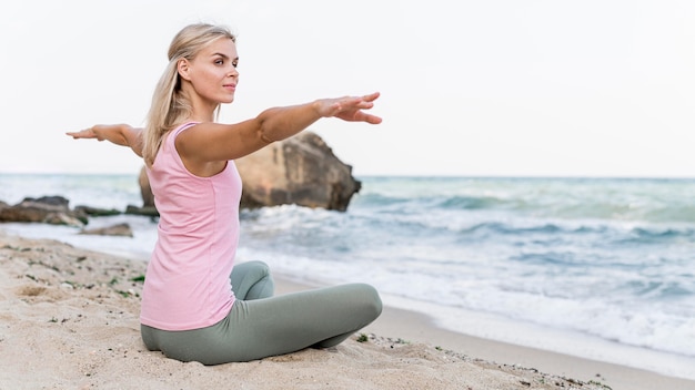 Bella donna a praticare yoga in spiaggia