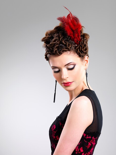 Bella donna adulta con acconciatura di moda con piuma rossa nei capelli