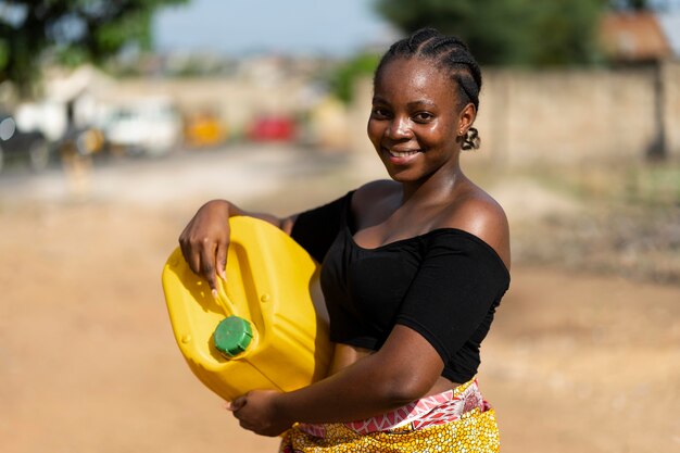 Bella donna africana che tiene un recipiente d'acqua giallo yellow