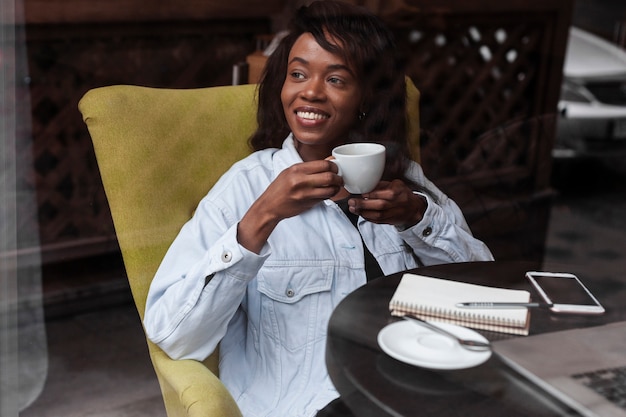 Bella donna afroamericana che mangia caffè