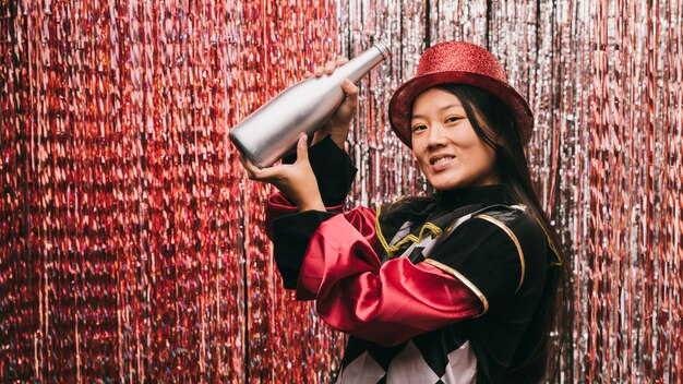 Bella donna alla festa di carnevale con bottiglia di champagne