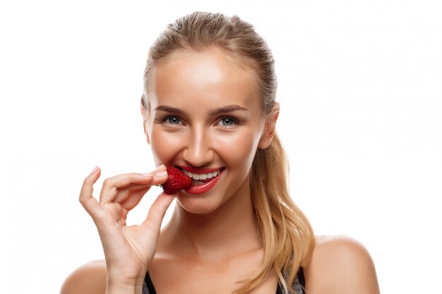 Bella donna allegra che posa, che mangia fragola