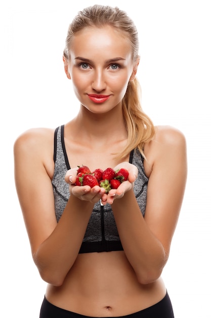 Bella donna allegra che posa, tenendo fragola