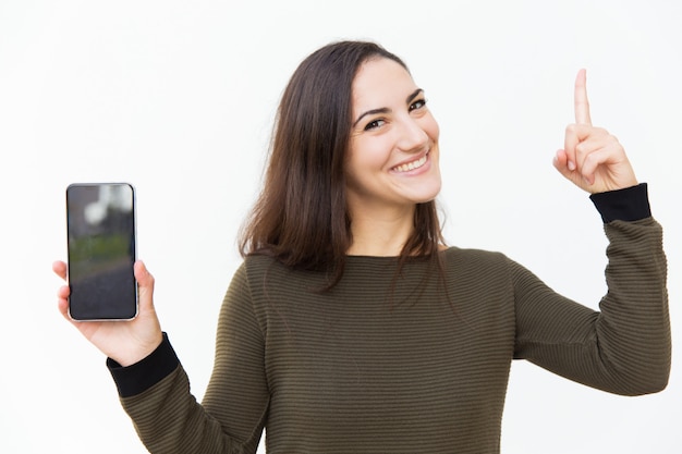 Bella donna allegra felice che mostra lo schermo in bianco dello smartphone