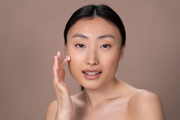 Bella donna asiatica che applica il trattamento della pelle