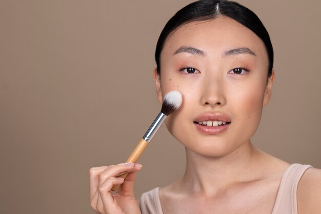 Bella donna asiatica che applica trucco