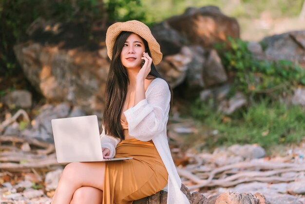 Bella donna asiatica che indossa il nuoto utilizzando il computer portatile sulla spiaggia in estate in vacanza