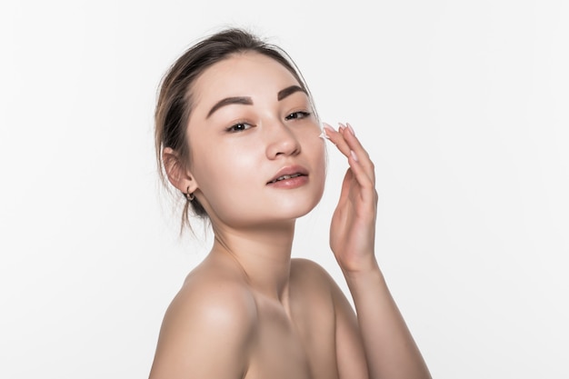 Bella donna asiatica che lava il suo fronte di bellezza con schiuma di pulizia sulle sue mani per cura di pelle isolata sulla parete bianca