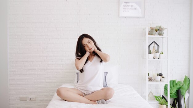 Bella donna asiatica che si estende il suo corpo dopo che si sveglia nella sua camera da letto a casa.