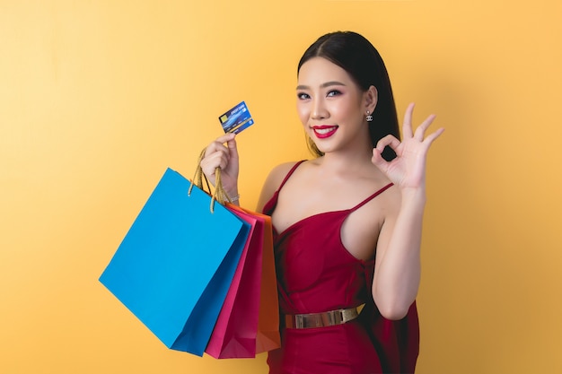 Bella donna asiatica con il sacchetto della spesa e la carta di credito a disposizione