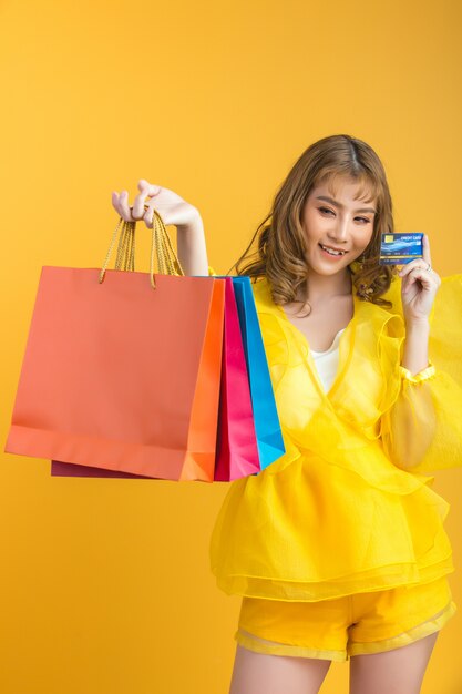 Bella donna asiatica con il sacchetto della spesa e la carta di credito a disposizione
