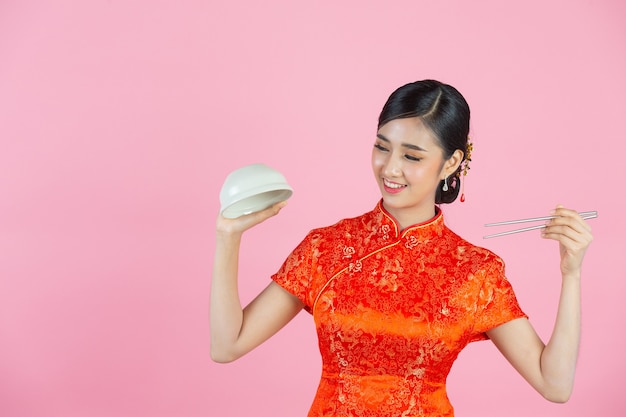 Bella donna asiatica sorriso felice e mangiare nel nuovo anno cinese su sfondo rosa.