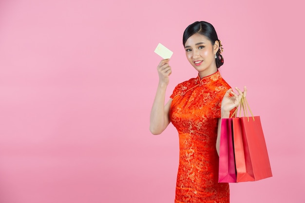 Bella donna asiatica sorriso felice e shopping nel capodanno cinese su sfondo rosa.