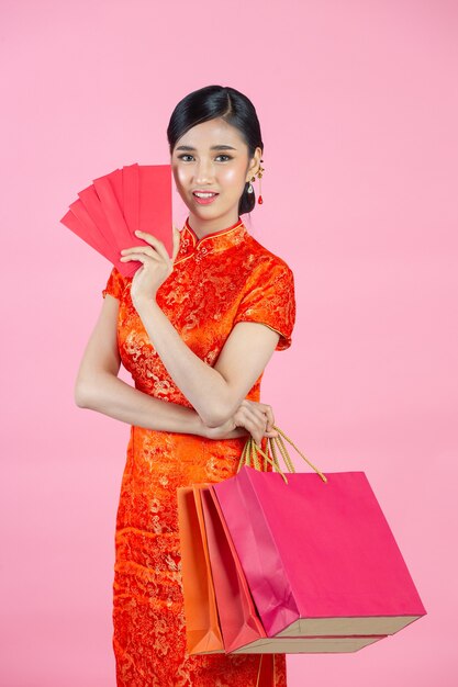 Bella donna asiatica sorriso felice e shopping nel capodanno cinese su sfondo rosa.