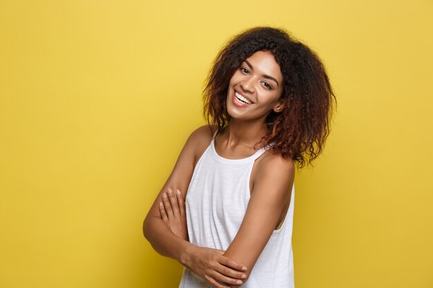 Bella donna attraente afroamericano con gli occhiali alla moda che postano sopra sfondo dello studio giallo. Copia spazio.