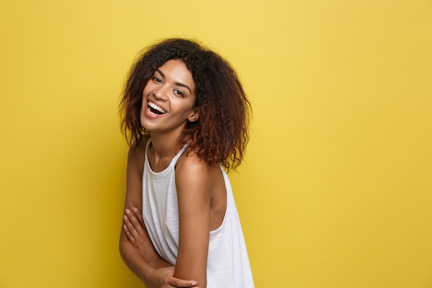 Bella donna attraente afroamericano con gli occhiali alla moda che postano sopra sfondo dello studio giallo. Copia spazio.