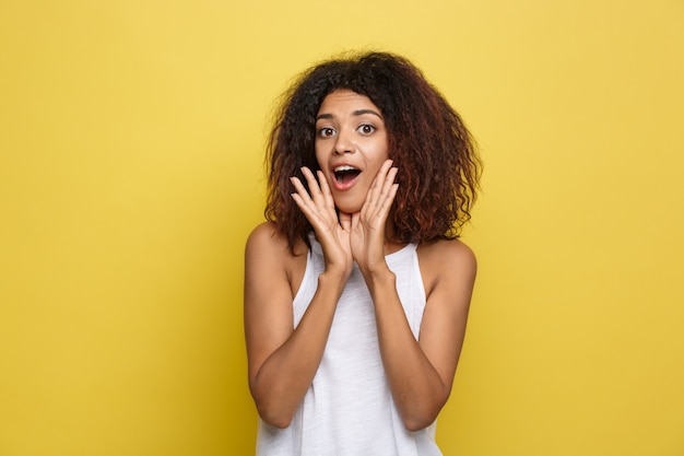 Bella donna attraente afroamericano con gli occhiali alla moda che postano sopra sfondo dello studio giallo. Copia spazio.