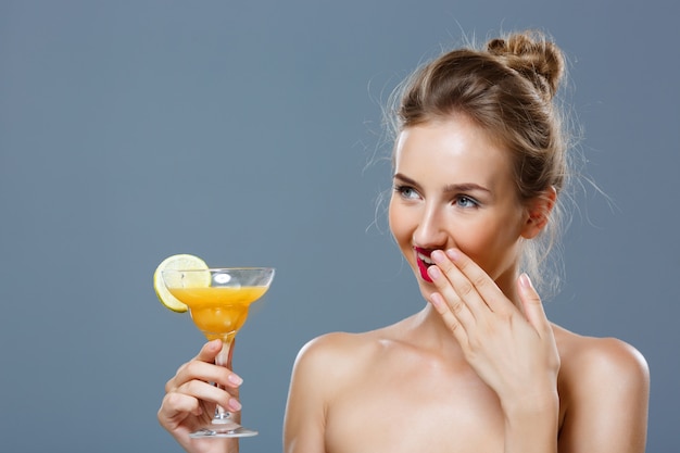 Bella donna bionda che sorride, tenendo cocktail