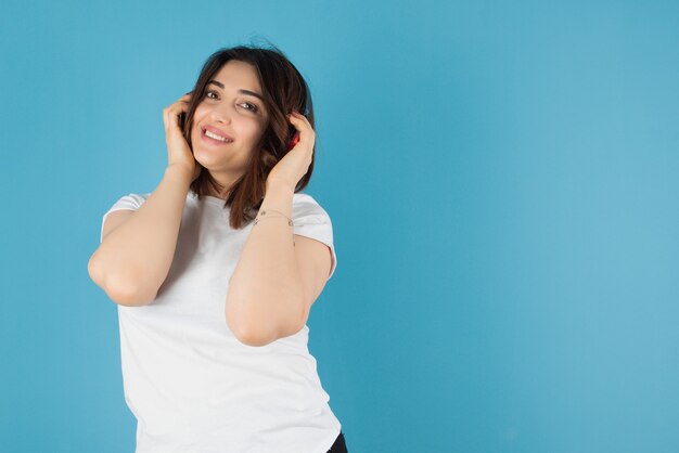 Bella donna castana che posa con le cuffie contro la parete blu