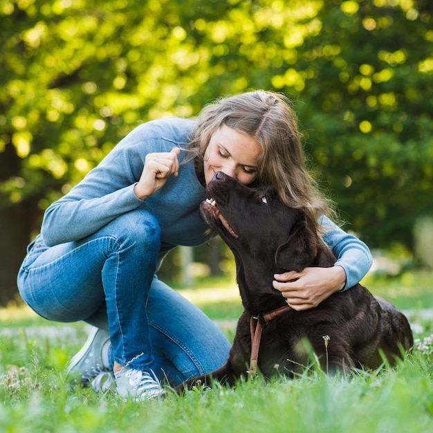 Bella donna che bacia il suo cane in giardino