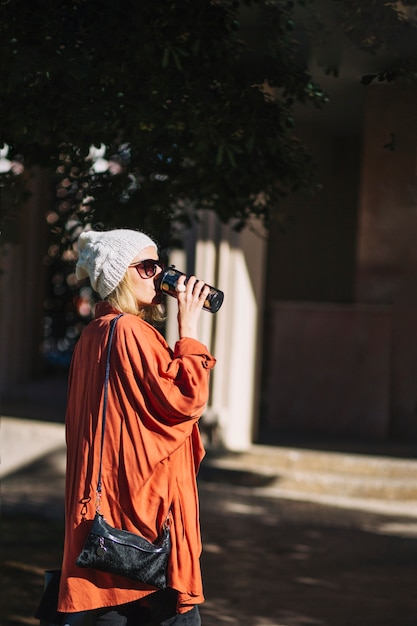 Bella donna che beve dal thermos sulla strada