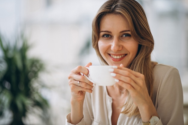 Bella donna che beve il caffè in un caffè
