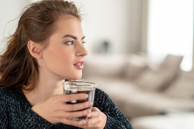 bella donna che beve il caffè la mattina a casa