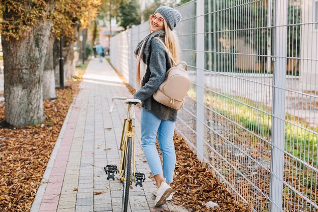 Bella donna che cammina con la bicicletta vicino al recinto