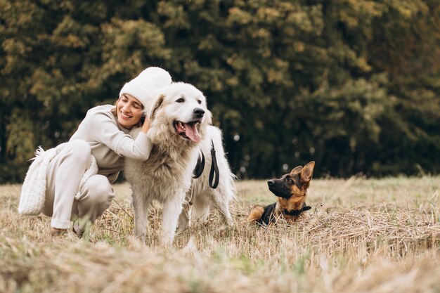 Bella donna che cammina fuori i suoi cani in un campo