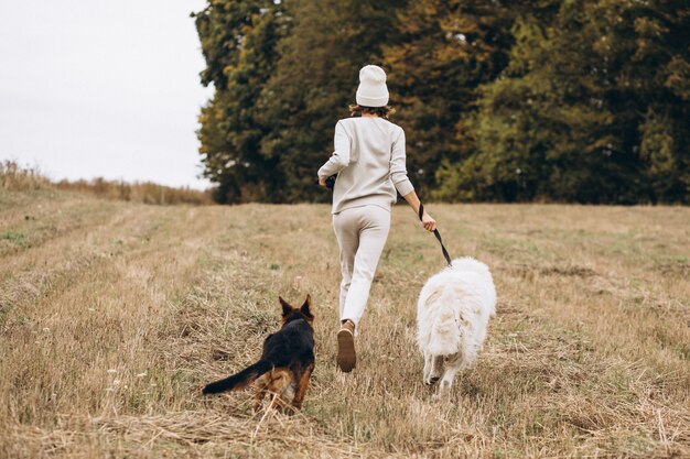 Bella donna che cammina fuori i suoi cani in un campo