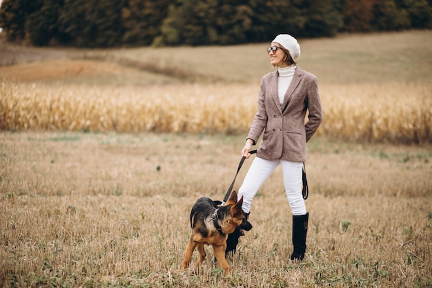 Bella donna che cammina fuori il suo cane in un campo