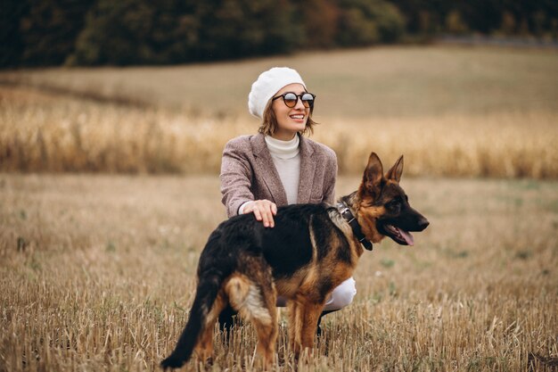 Bella donna che cammina fuori il suo cane in un campo