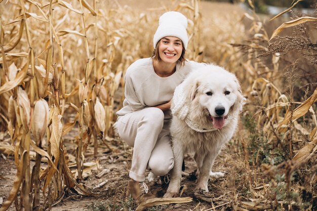 Bella donna che cammina fuori il suo cane in un campo