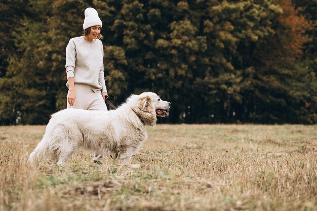 Bella donna che cammina fuori il suo cane in un campo