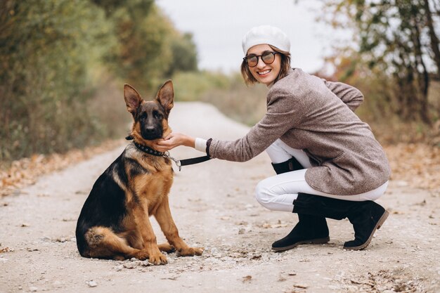 Bella donna che cammina fuori il suo cane nel parco di autunno