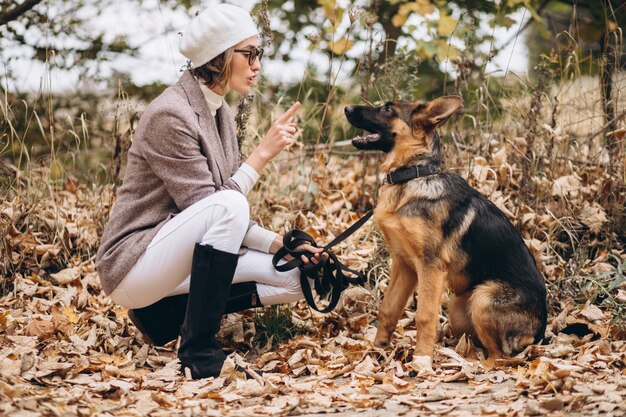 Bella donna che cammina fuori il suo cane nel parco di autunno