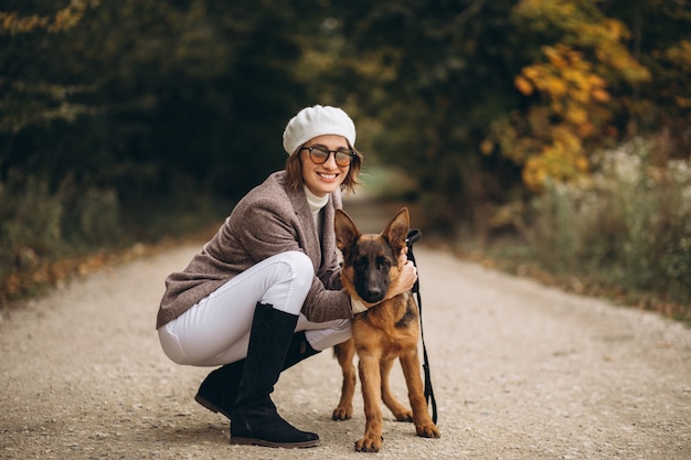 Bella donna che cammina fuori il suo cane nel parco di autunno