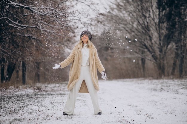 Bella donna che cammina nel parco pieno di neve