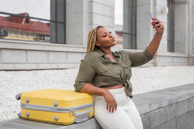 Bella donna che cattura un selfie accanto al suo bagaglio