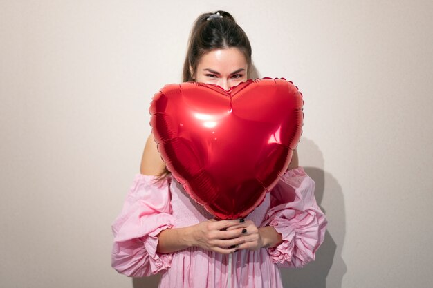 Bella donna che celebra il giorno di San Valentino in un vestito rosa con palloncini