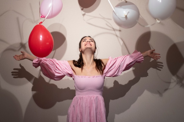 Bella donna che celebra il giorno di San Valentino in un vestito rosa con palloncini