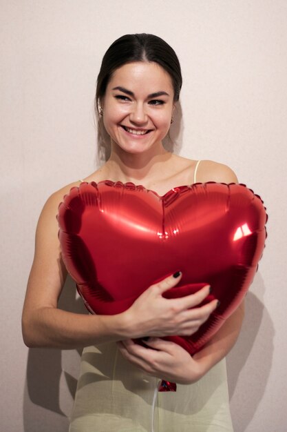Bella donna che celebra il giorno di San Valentino mentre tiene in mano un palloncino rosso a forma di cuore