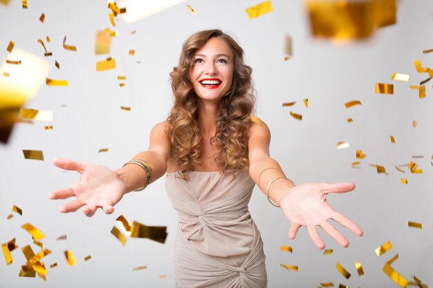 Bella donna che celebra il nuovo anno in coriandoli dorati