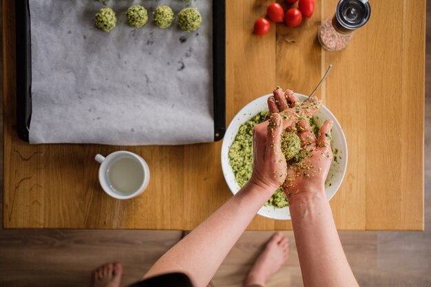 Bella donna che cucina falafel sulla tavola di legno