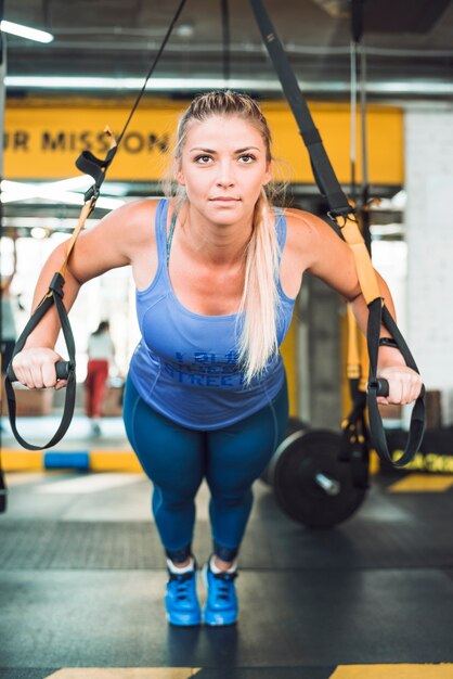 Bella donna che fa esercizio con trappola di fitness in palestra