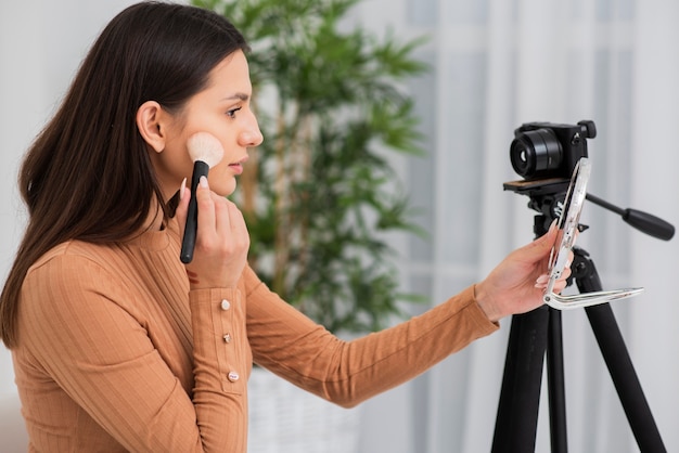 Bella donna che fa il suo trucco sulla macchina fotografica