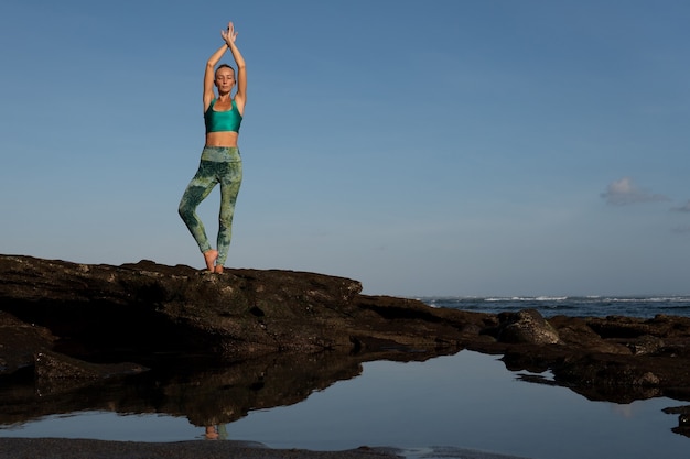 Bella donna che fa yoga sulla spiaggia