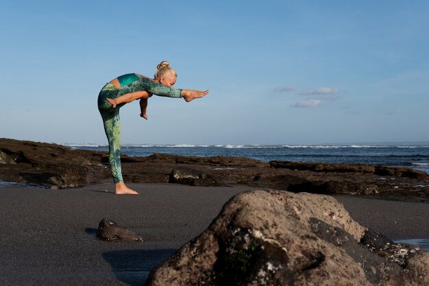 Bella donna che fa yoga sulla spiaggia