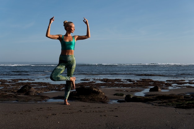 Bella donna che fa yoga sulla spiaggia